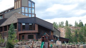 A modern building with a large glass window, a stone wall, and a green slide. - Large newly updated condo in close proximity to town and summer adventures!  (Durango)