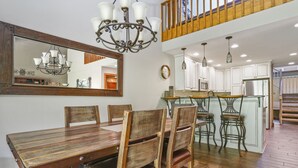 A dining area with a wooden table and chairs, a chandelier, and a kitchen in the background. - Large newly updated condo in close proximity to town and summer adventures!  (Durango)