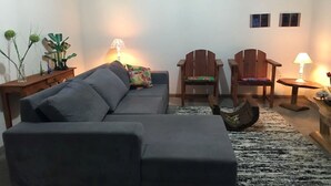 A living room with a grey sofa, two wooden chairs, a small table, and a lamp. - Paraiso in Bahia - house by the sea in the middle of coconut trees (Belmonte)