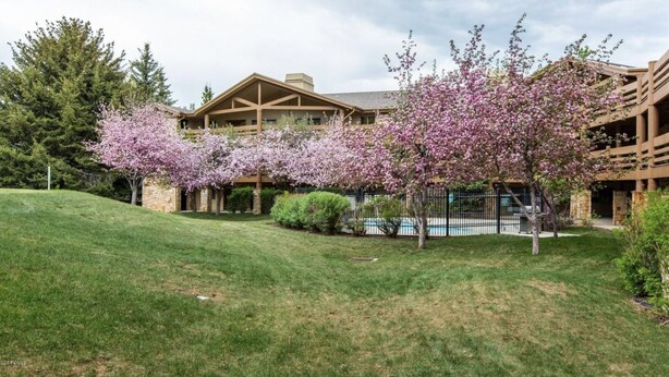 Un chalet avec une façade en pierre, une terrasse en bois et une piscine.