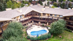 Ein mehrgeschossiges Gebäude mit einem zentralen Innenhof, der einen Swimmingpool, Sitzmöglichkeiten im Freien und einen eingezäunten Bereich bietet.