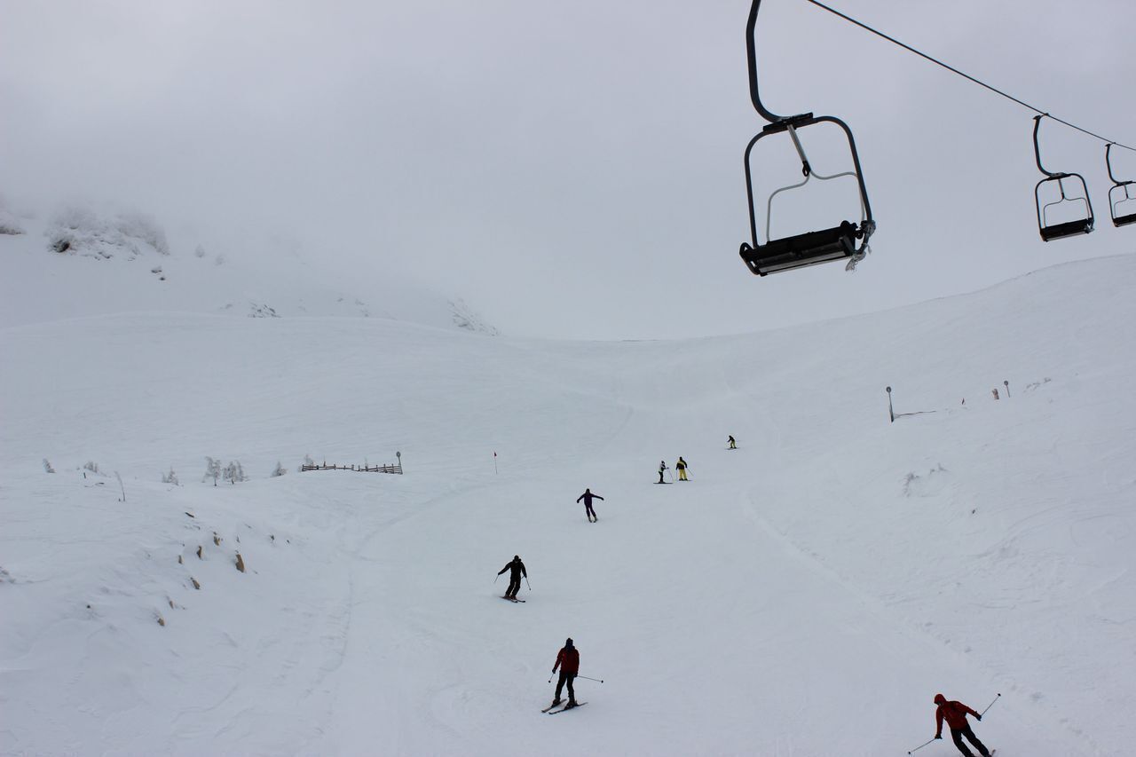 A ski slope with a ski lift and skiers descending.