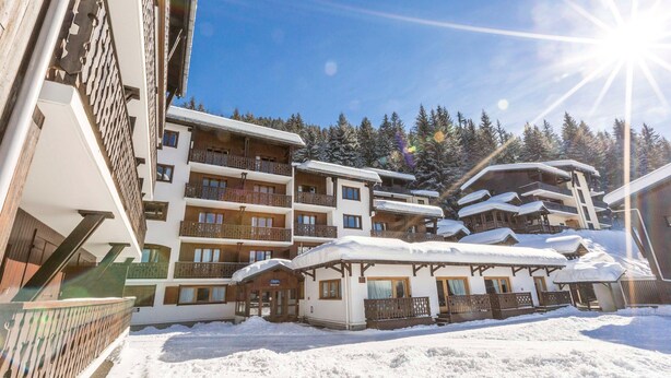 A multi-story hotel with balconies and a snow-covered landscape.