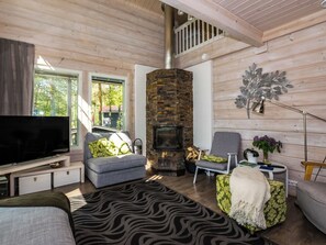 A cozy living room with a stone fireplace, a television, and comfortable seating. - Villa ina by Interhome (Evijärvi)