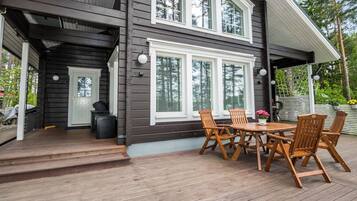Ein zweigeschossiges Haus mit einer Terrasse, Sitzgelegenheiten im Freien und einer Garage.