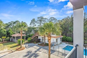 A residential property with a swimming pool, a covered patio, and a garden area with palm trees.