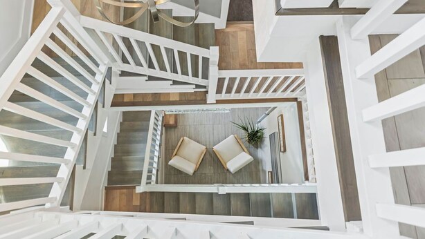 A modern interior with a spiral staircase, white railings, and a central seating area with two sofas and a plant.