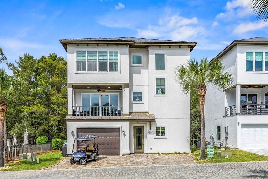 A two-story residential building with a garage, a balcony, and a golf cart parked in front.