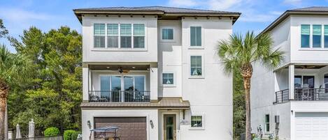 A two-story residential building with a garage, a balcony, and a golf cart parked in front.