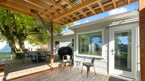 A covered patio with wooden flooring, outdoor furniture, and a barbecue grill. - Cottage near Vancouver Lake! Cozy, Clean, & Comfortable w/ new Pickleball Court! (Vancouver)