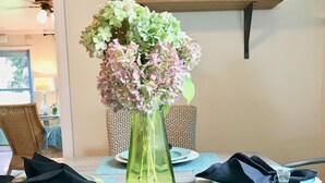 A dining table with teal placemats, plates, and napkins. A green vase with flowers is centered on the table. - Cottage near Vancouver Lake! Cozy, Clean, & Comfortable w/ new Pickleball Court! (Vancouver)