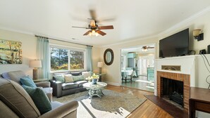 A living room with a sofa, coffee table, fireplace, and a television mounted above the fireplace. - Cottage near Vancouver Lake! Cozy, Clean, & Comfortable w/ new Pickleball Court! (Vancouver)