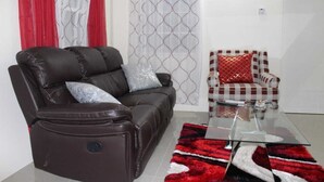 A living room with a brown leather sofa, a glass coffee table, and a patterned rug. - A single family home in a secure gated community where you can feel at home (Florence Hall Village)