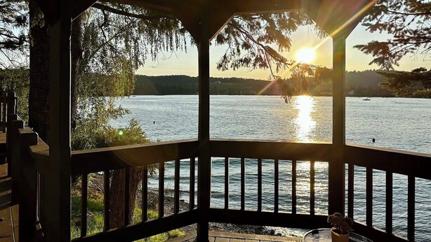 A wooden deck with a view of a lake and sunset.