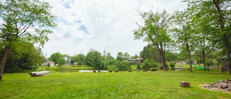 A grassy outdoor area with trees, a flagpole, and a hammock.
