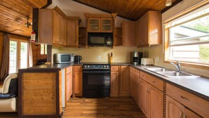 A kitchen with wooden cabinets, a microwave, a stove, and a sink. - Beautiful 3 Bdrm + Bunkie waterfront cottage near Gull Lake (Minden Hills)