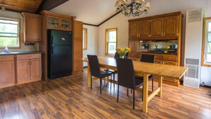 A spacious kitchen with wooden cabinets, a black refrigerator, a wooden dining table with chairs, and a chandelier. - Beautiful 3 Bdrm + Bunkie waterfront cottage near Gull Lake (Minden Hills)