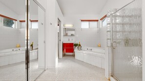 Ein modernes Badezimmer mit weißen Fliesen, einem roten Schrank und einer Duschkabine aus Glas.