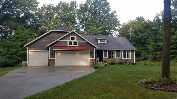 A two-story house with a garage, a red roof, and a well-maintained lawn.