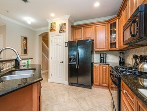 A kitchen with wooden cabinets, a black refrigerator, a stove, and a sink.