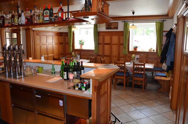 A kitchen with a bar area, wooden cabinets, a dishwasher, and a dining table with chairs.