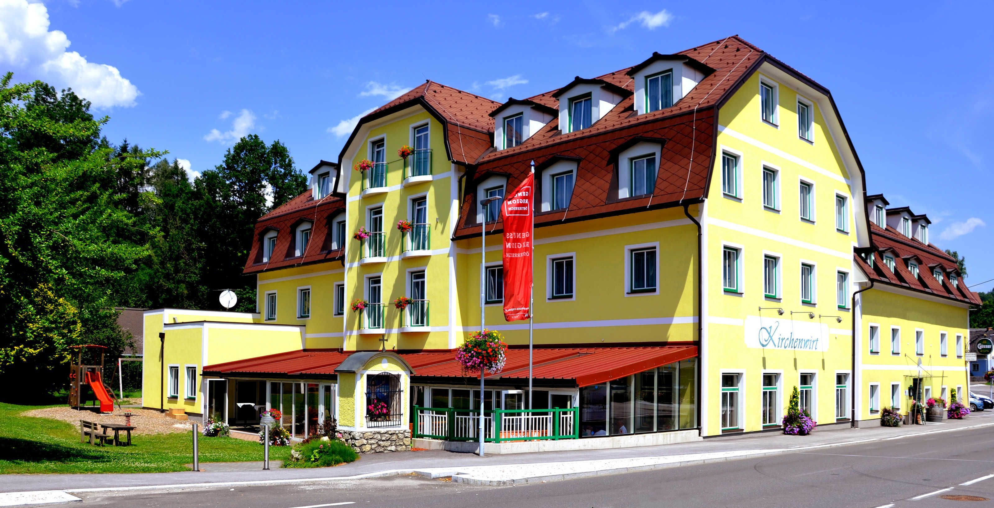 A yellow building with a red awning, a flag, and a sign that reads 'Kirchenwirt.'