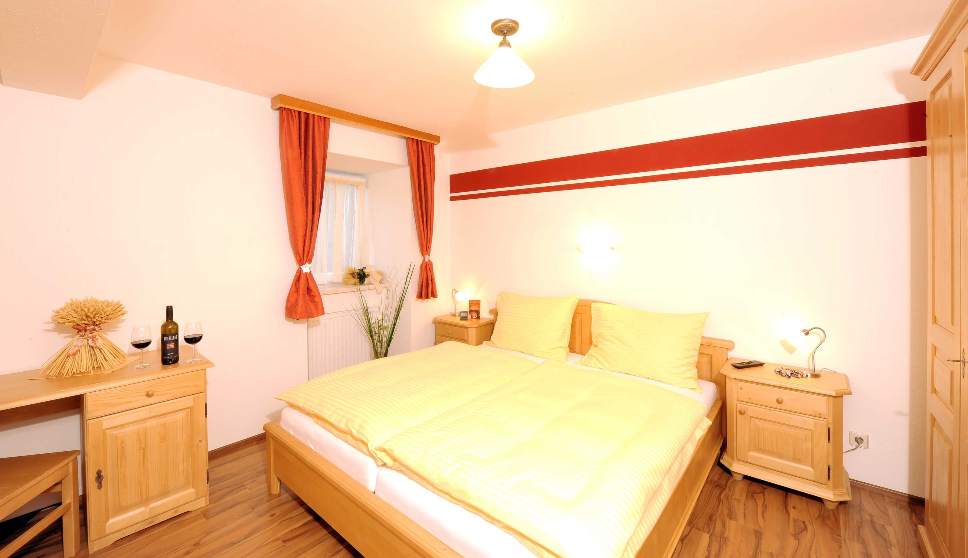 Un dormitorio con una cama, mesitas de noche de madera, un aparador y un espejo.