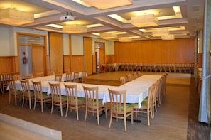 Ett konferensrum med långa bord och stolar, träpanel på väggarna och takbelysning.
