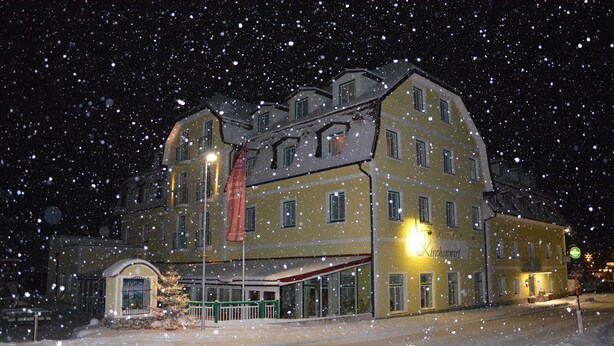 Un edificio cubierto de nieve con múltiples ventanas, una bandera y un letrero que indica un restaurante.