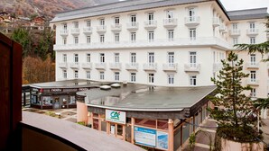 A multi-story hotel with balconies, a sign for 'Agence Provisoire', and a view of a mountainous area. - Renovated studio for 4 people with washer, wifi (Brides-les-Bains)