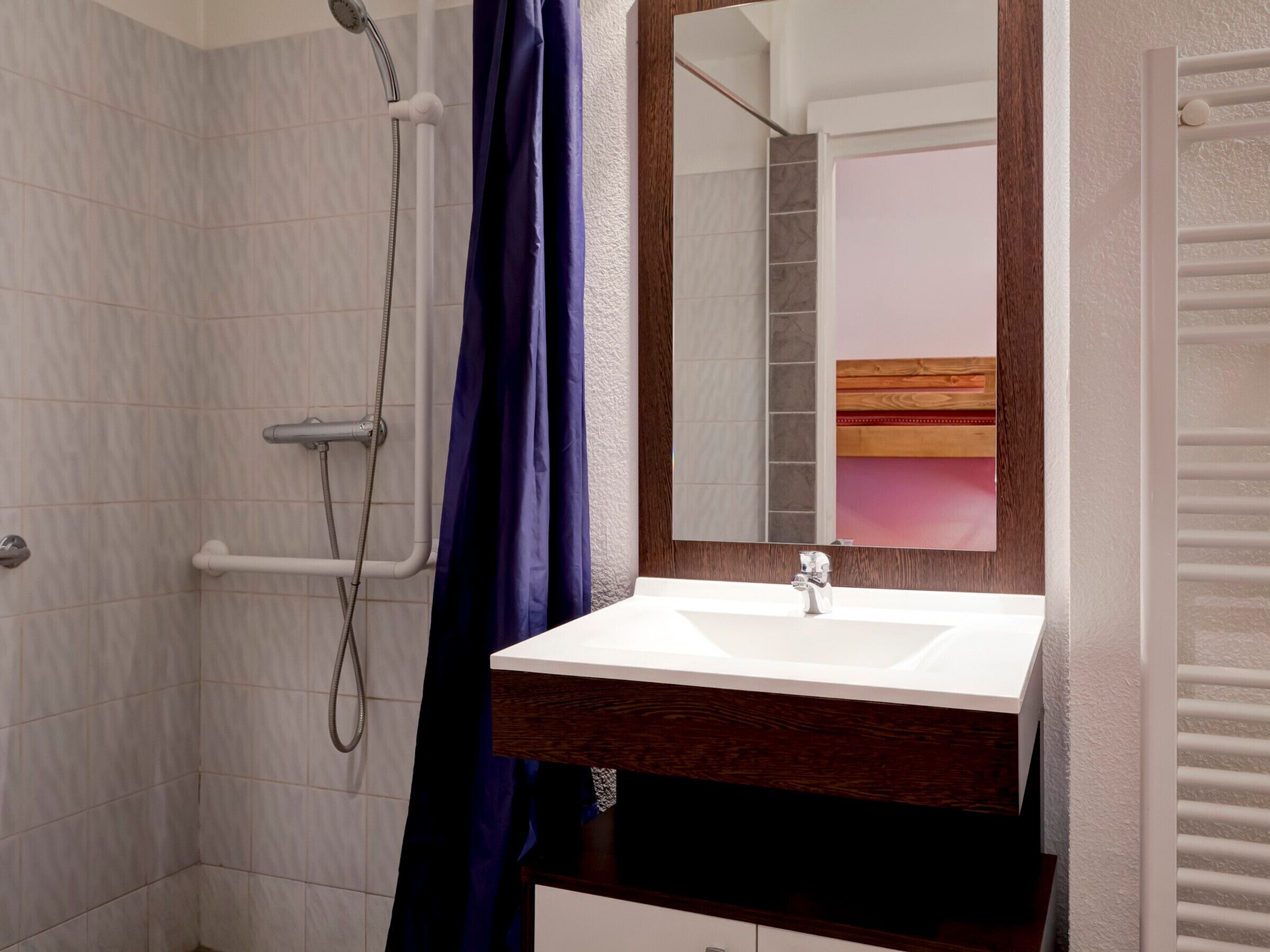 Un baño con ducha, lavamanos y espejo.