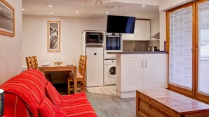 A compact living space with a dining area, kitchenette, and a sofa. - 4-room apartment with balcony, internet, parking in the center of Brides-les-Bains (Brides-les-Bains)