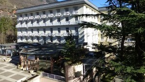 A multi-story hotel with balconies, a checkered pavement, and a mountain backdrop. - 2* Studio with Wifi in Brides-les-Bains Center (Brides-les-Bains)