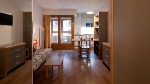 A compact living space with a kitchenette, a dining area, and a sofa. - 2* Studio with balcony, parking and wifi in the heart of Brides-les-Bains (Brides-les-Bains)