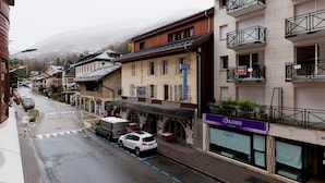 A street with buildings, a restaurant, and a sign for 'Couleurs Paris'. - 2* Studio with balcony, parking and wifi in the heart of Brides-les-Bains (Brides-les-Bains)
