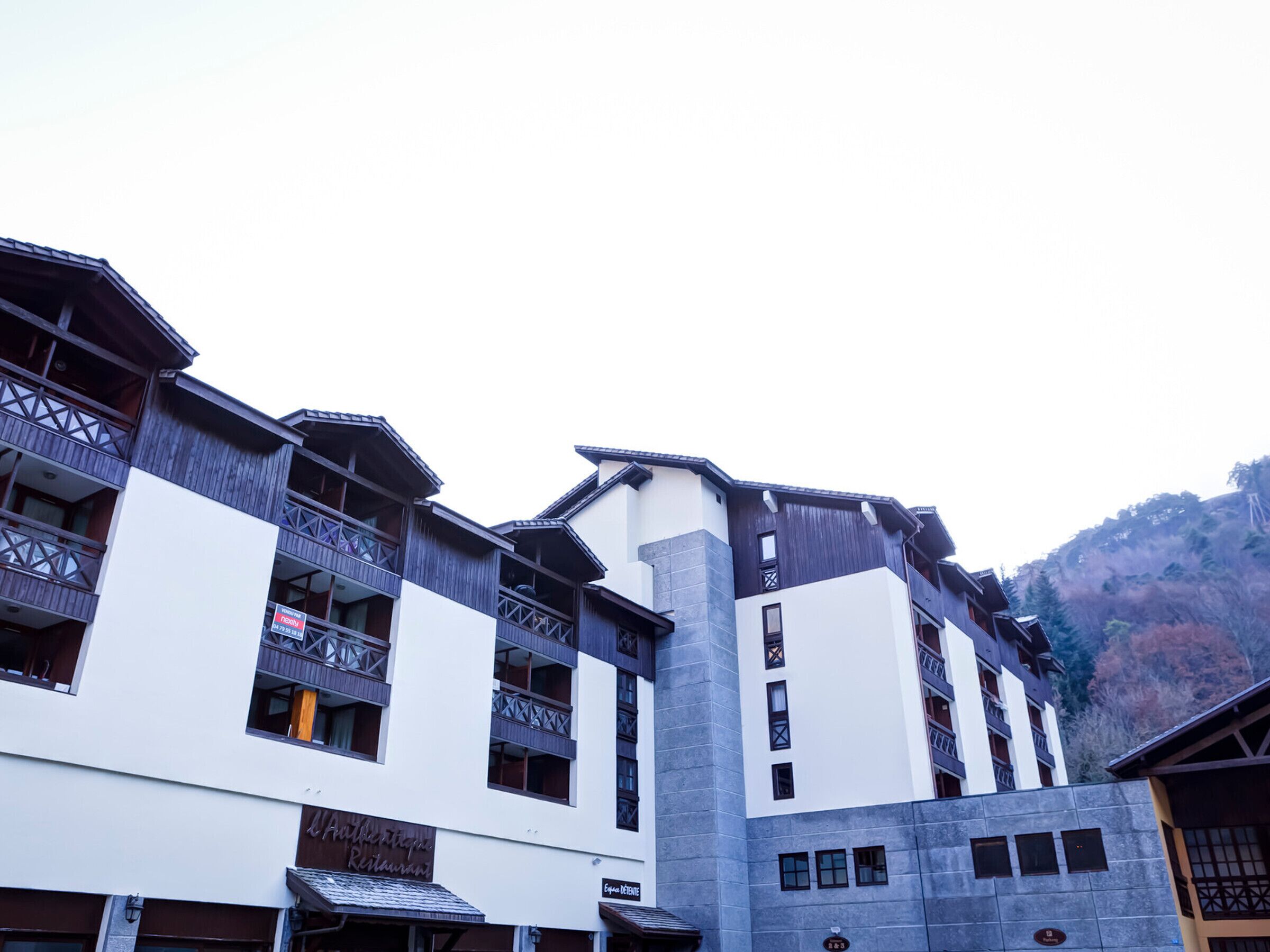 Ein mehrstöckiges Hotel mit Balkonen, einem Restaurant und einem Schild, das auf ein nahegelegenes Skigebiet hinweist.