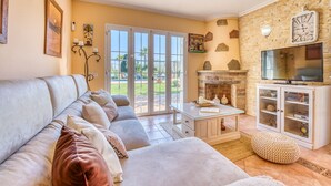 A living room with a sofa, a coffee table, a fireplace, a television, and a stone wall. - Finca in Mallorca Can Caragol Inca with pool (Inca)