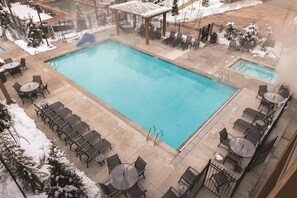 Une piscine rectangulaire avec un toboggan, entourée de chaises longues et de tables.