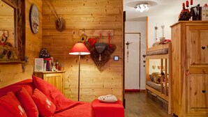 Una habitación acogedora con detalles de madera, un sofá rojo, una lámpara y una cama nido.