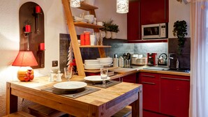 Una cocina moderna con armarios rojos, una mesa de comedor de madera y luces colgantes.