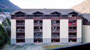 A multi-story hotel with balconies, set against a mountainous backdrop.