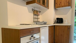 Eine kleine Küche mit Holzschränken, einer weißen Arbeitsplatte, einem eingebauten Backofen und einer Kaffeemaschine.