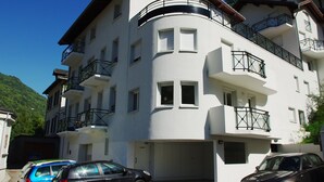 Ein mehrgeschossiges Gebäude mit Balkonen, einer Garage und einem geparkten Auto davor.