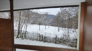 A view through a wooden-framed window of a snow-covered landscape with trees and a fence. - Cozy Studio with WiFi and Parking - Sleeps 4 (Brides-les-Bains)