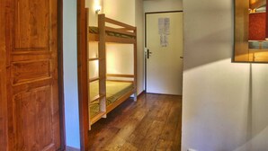 A hallway with a wooden door, a bunk bed, and a door with a notice. - Cozy Studio with WiFi and Parking - Sleeps 4 (Brides-les-Bains)