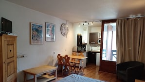 A compact room with a bed, a desk, and a chair. There is a kitchenette in the background. - 2* Studio for 4 with mountain view, parking included, pets allowed (Brides-les-Bains)