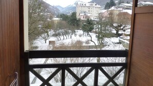 A view from a window with a wooden frame, overlooking a snowy landscape with buildings and trees. - 2* Studio for 4 with mountain view, parking included, pets allowed (Brides-les-Bains)