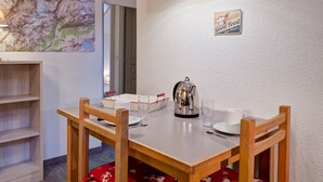 A dining area with a table set for two, a kettle, and a sign indicating a 24-hour food service.