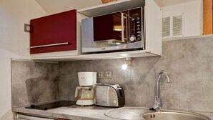 A compact kitchen with a built-in microwave, a coffee maker, a toaster, and a sink.
