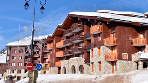 A multi-story wooden building with balconies, stone walls, and a snow-covered roof.